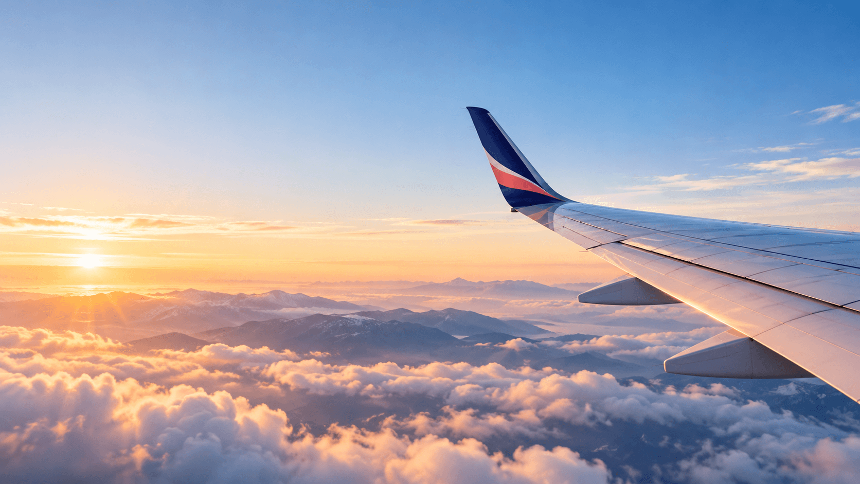 View of an aircraft wing above the clouds at sunset